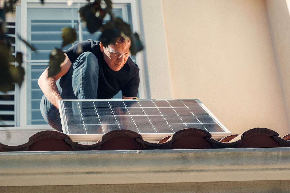 Homem em cima do telhado instalando painéis solar
